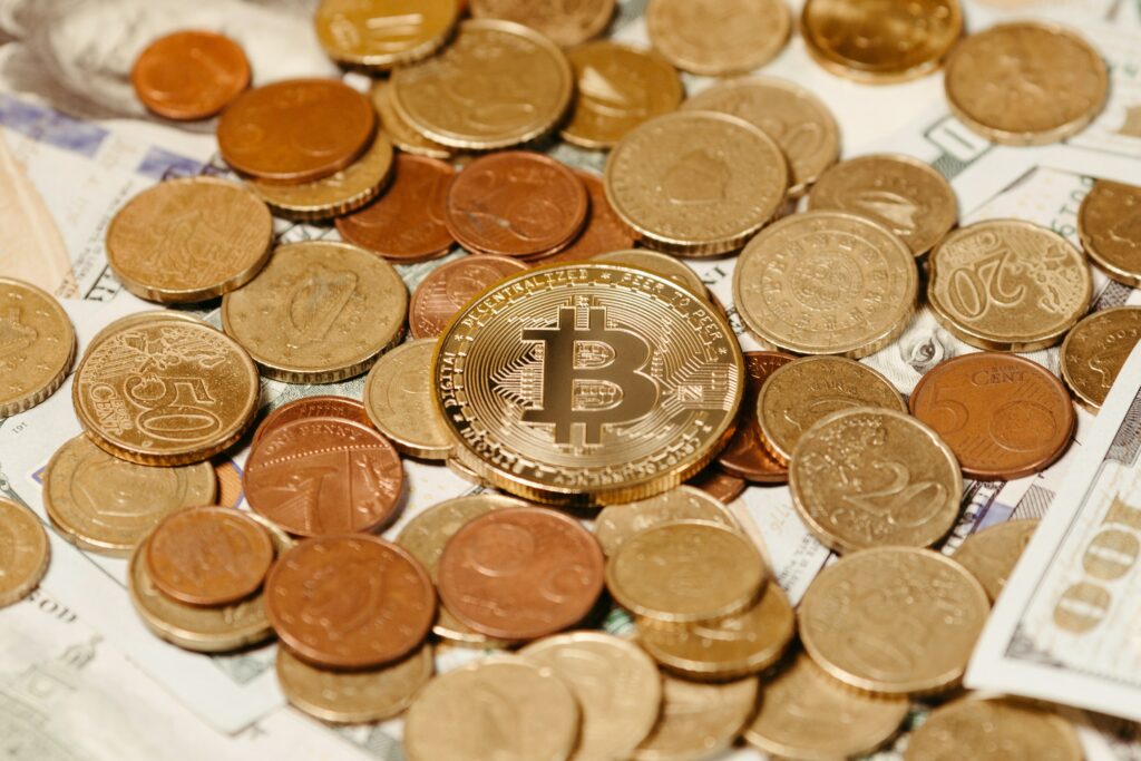 A variety of physical coins and paper money of different denominations with a Bitcoin placed centrally on top of them